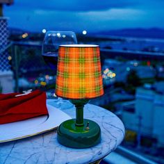 a lamp sitting on top of a table next to a wine glass and napkins