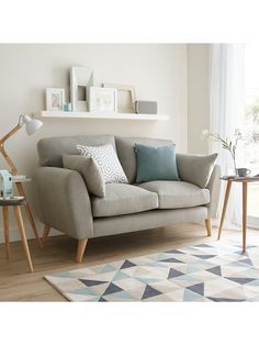 a living room scene with focus on the couch and rug in front of the window