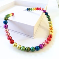 a multicolored necklace sitting on top of a white box