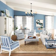 a living room with blue walls and white furniture in the center, along with a chandelier