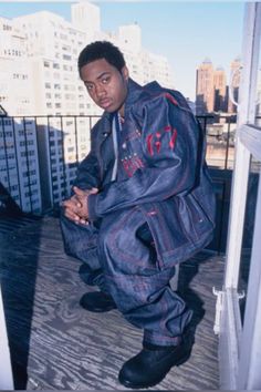 a man sitting on top of a wooden floor next to tall buildings in the background