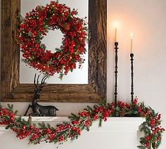 a christmas mantle with wreaths and candles on it in front of a framed mirror