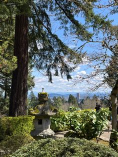 a stone lantern in the middle of a garden with trees and bushes around it on a sunny day