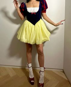 a woman dressed as snow white is standing in front of a wall with her hands out