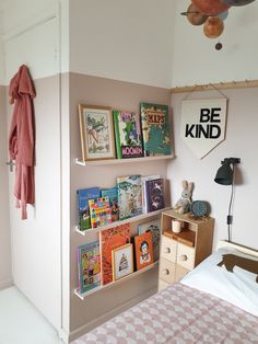 a child's bedroom with pink walls and bookshelves on the wall next to a bed