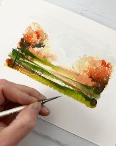 someone is painting trees with watercolors on paper