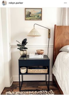 a bed room with a neatly made bed and a night stand next to a lamp