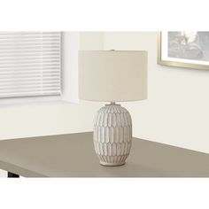 a table lamp sitting on top of a wooden table next to a window with blinds