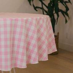 a pink and white checkered table cloth on top of a wooden chair next to a potted plant