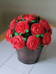 cupcakes with red frosting and green leaves in a flower pot on the floor