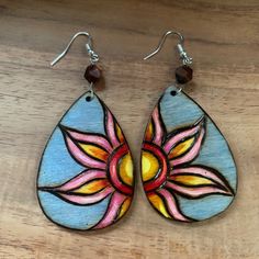 a pair of wooden earrings with painted designs on them, sitting on a wood table