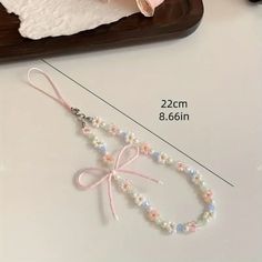 the beaded necklace is next to a pink rose