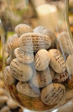 a glass vase filled with lots of rocks and writing on the inside, sitting on top of a table