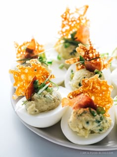 deviled eggs topped with bacon and garnish on a plate