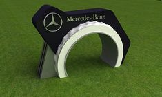 the mercedes benz logo is on display in an open field with green grass and blue sky