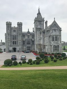 two cars parked in front of a large castle like building with tall towers and arched windows