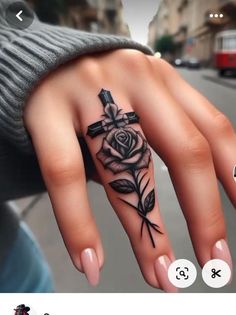 a woman's hand with a cross and rose tattoo on it