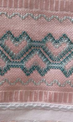 a piece of cloth with some green beads on it and pink fabric in the background