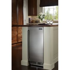 a silver refrigerator freezer sitting inside of a kitchen next to a counter with wine glasses on it