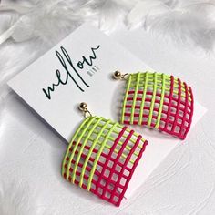 neon green, pink and yellow earrings on a white card with feathers in the background