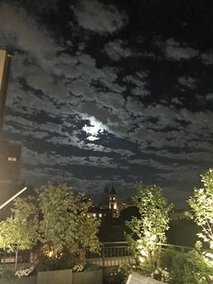 the night sky is lit up with clouds and stars in the distance, as seen from an apartment balcony