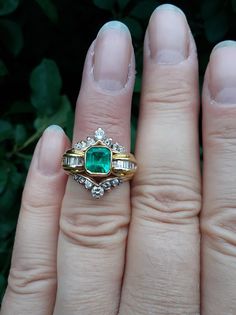 a close up of a person's hand with a ring on her finger and an emerald stone in the middle