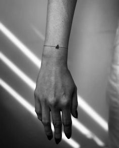 a person's hand with a tiny bird tattoo on their left wrist and the other arm