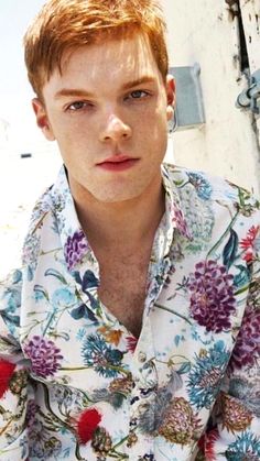 a young man with red hair wearing a flowered shirt and looking at the camera