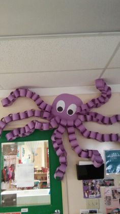 a purple octopus hanging on the wall next to a green frame with eyes and arms