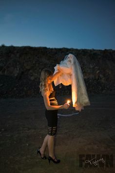 a woman holding a lit candle in her hand and wearing a wedding veil over her head