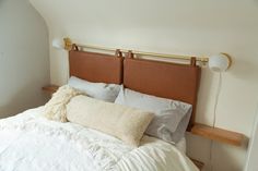 a bed with white linens and pillows on it's headboard is shown