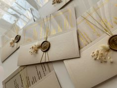 wedding stationery with gold foiling and buttons on white envelopes, along with other items