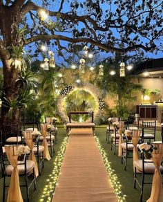 an outdoor wedding venue set up with white linens and greenery, lit by lights