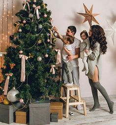 a family decorates a christmas tree in their living room