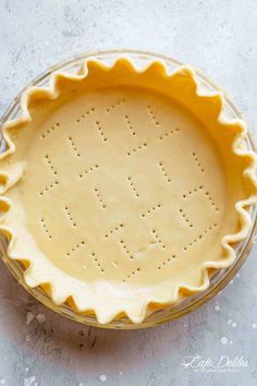 an uncooked pie crust in a glass pie dish on a white table top