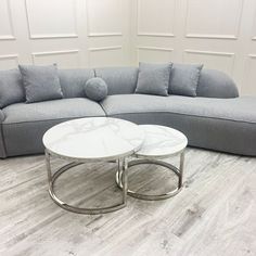 a white marble coffee table sitting on top of a wooden floor next to a gray couch