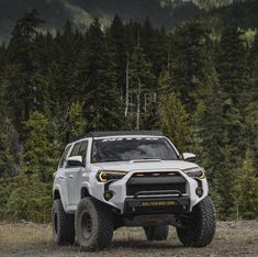 the front end of a white four - doored suv parked on a dirt road