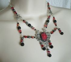 "This beautiful necklace has red glass beads, black pearl beads, seed beads, sterling silver plated filigree beads, pewter silver accent beads, sterling silver plated accents, sterling silver plated chain, sterling silver plated pendant and a red rose cameo. It can be worn as a choker or adjusted up to 20\" long. Lobster clasp." Gothic Metal Jewelry With Black Beads, Gothic Black Beaded Metal Jewelry, Gothic Beaded Necklace For Gift, Gothic Pendant Jewelry For Festivals, Adjustable Red Gothic Jewelry, Handmade Gothic Jewelry For Festivals, Handmade Gothic Jewelry For Party, Gothic Black Beads Necklace For Jewelry Making, Gothic Silver Necklace With Black Beads