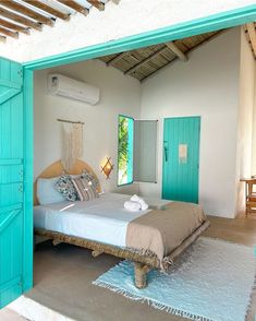 a bed sitting in the middle of a bedroom next to a blue door and window