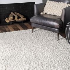 a living room with a chair, rug and fireplace