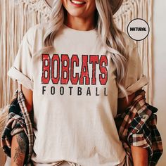 Elevate your Football Game day apparel with this Unisex super soft Customized football shirt.  Customize the front with your school of choice & color.  These shirts are perfect for men or women. These shirts are made of high-quality cotton.  Thank you for browsing our shop, we hope you find something you enjoy! If there is a shirt color not shown that you want, write in personalization field and we can make it happen. *Check out our other sports options here* https://www.etsy.com/shop/DesertSunr Custom Football Shirts, Mascot Shirt, Tshirt Custom, Dashboard Header, Custom Football, School Mascot, Football Game, Football Season, School Spirit