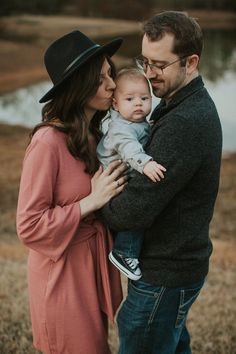 a man and woman holding a baby in their arms