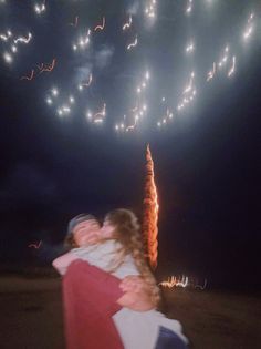 two people hugging each other with fireworks in the background