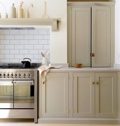 a kitchen with an oven, stove and cupboards in white painted wood paneling