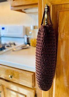 a crocheted bag hanging from the side of a kitchen cabinet