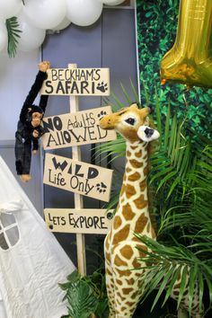 a stuffed giraffe standing next to a sign