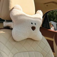 a teddy bear sitting in the back seat of a car with it's head hanging out