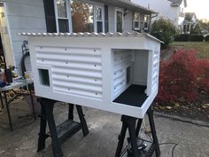 a large white birdhouse sitting on top of a metal stand in front of a house