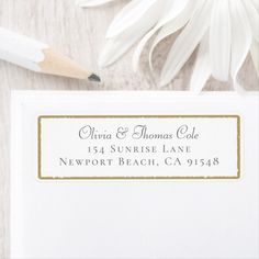 a close up of a white envelope with a pencil on it next to some flowers