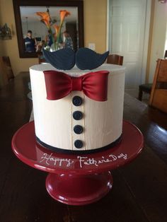 a birthday cake decorated with a bow tie and tuxedo on a red plate